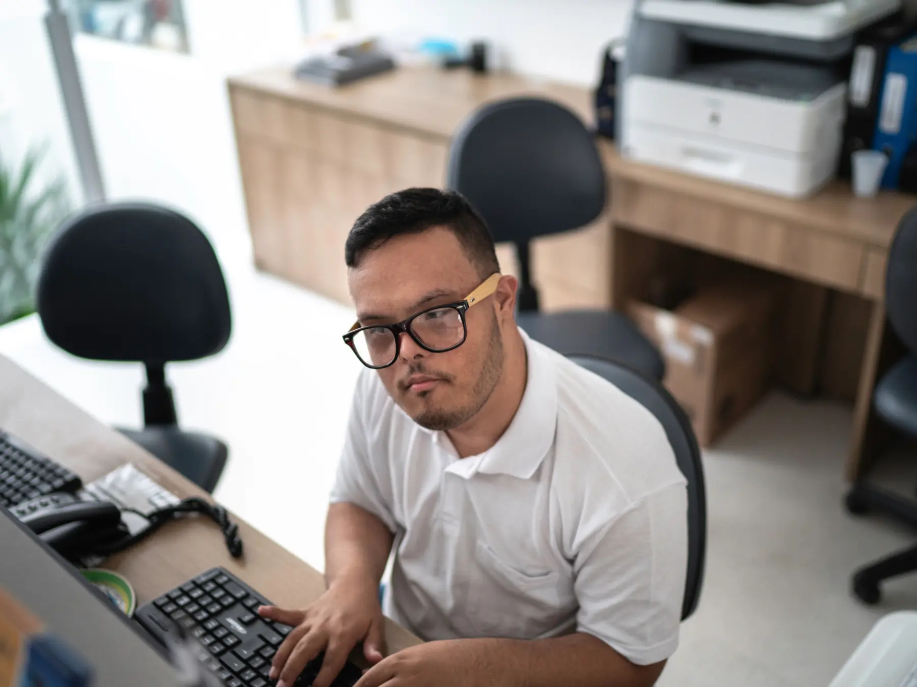 An adult working independently at a computer in an office