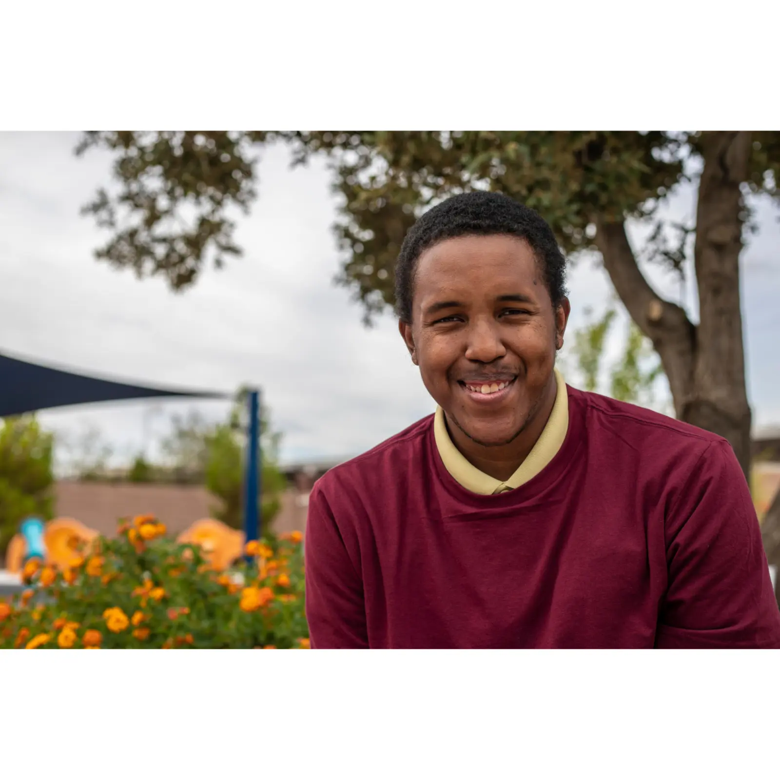 An adult smiling outdoors in his community