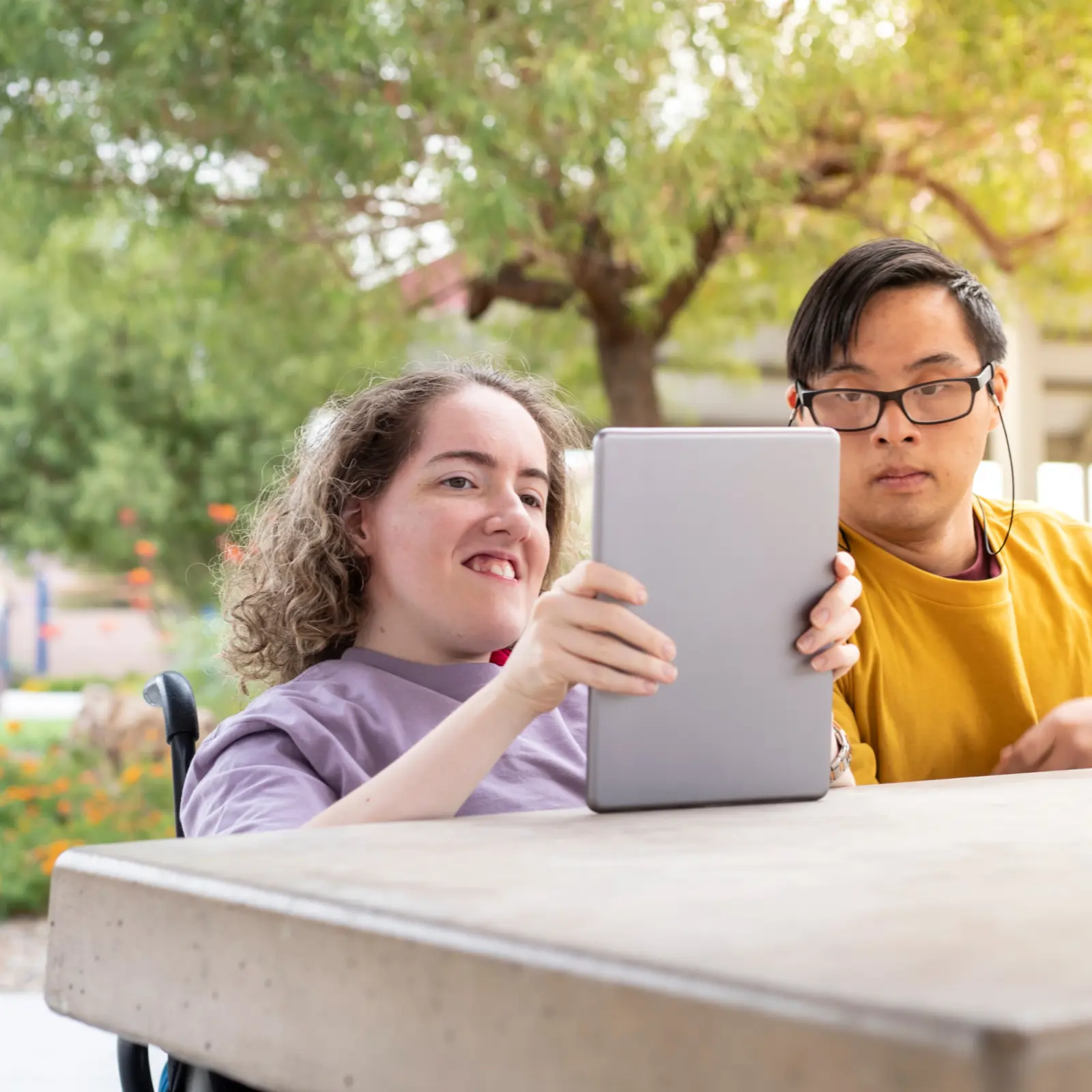 Two adults using a tablet for communication support